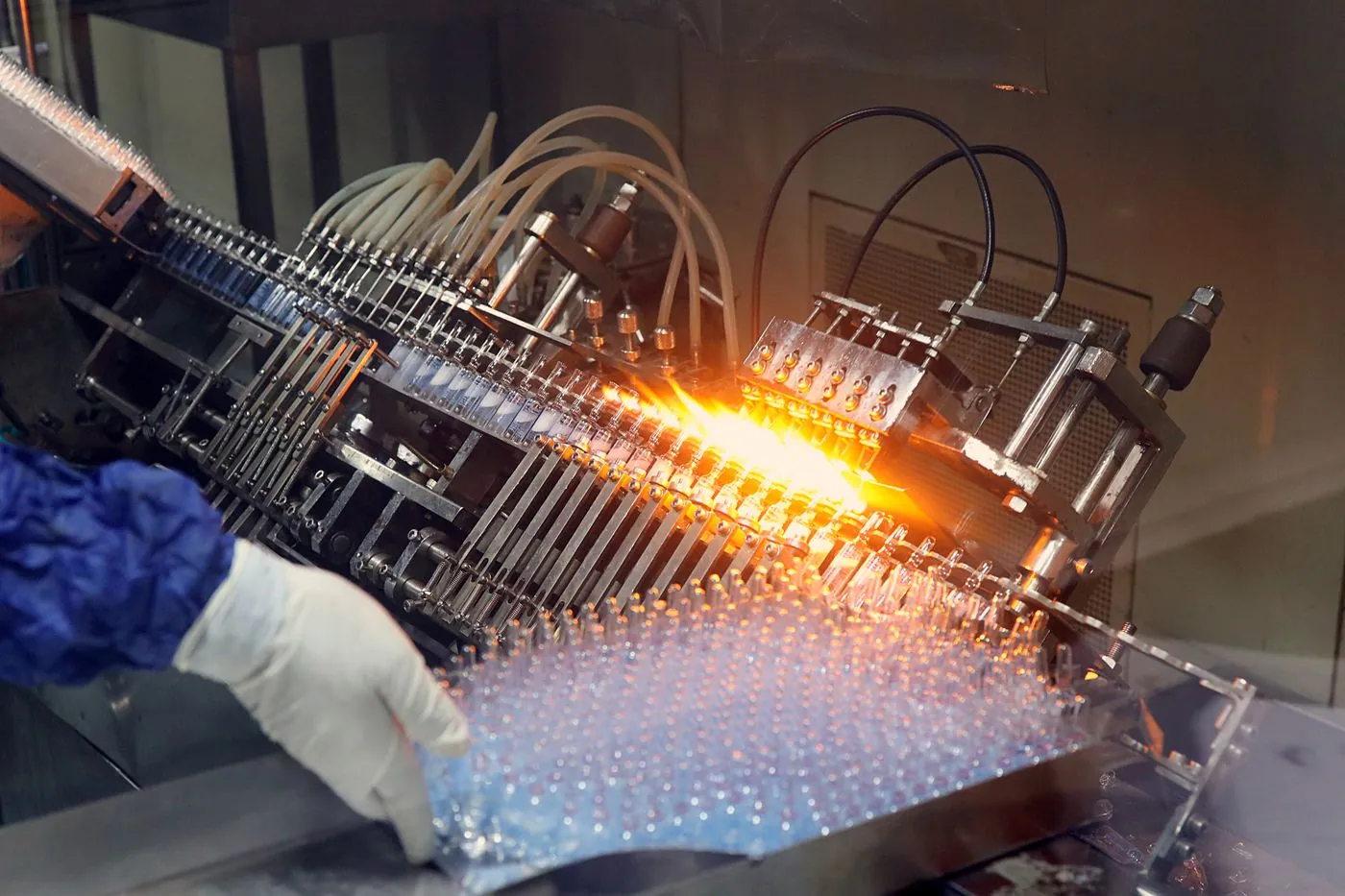 Ampoules being filled and sealed on a pharmaceutical production line.