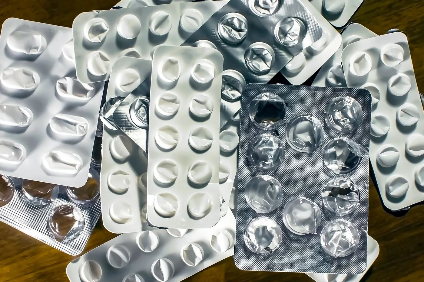 A pile of used and unused blister packs on a wooden surface.