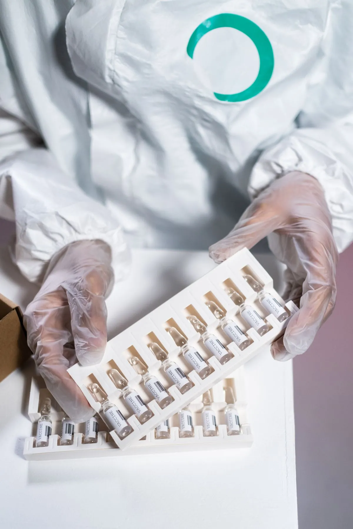 Gloved hands in a laboratory holding a blister pack of tablets.