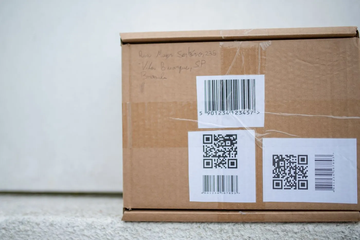 A shipping carton printed with QR codes and linear barcodes.