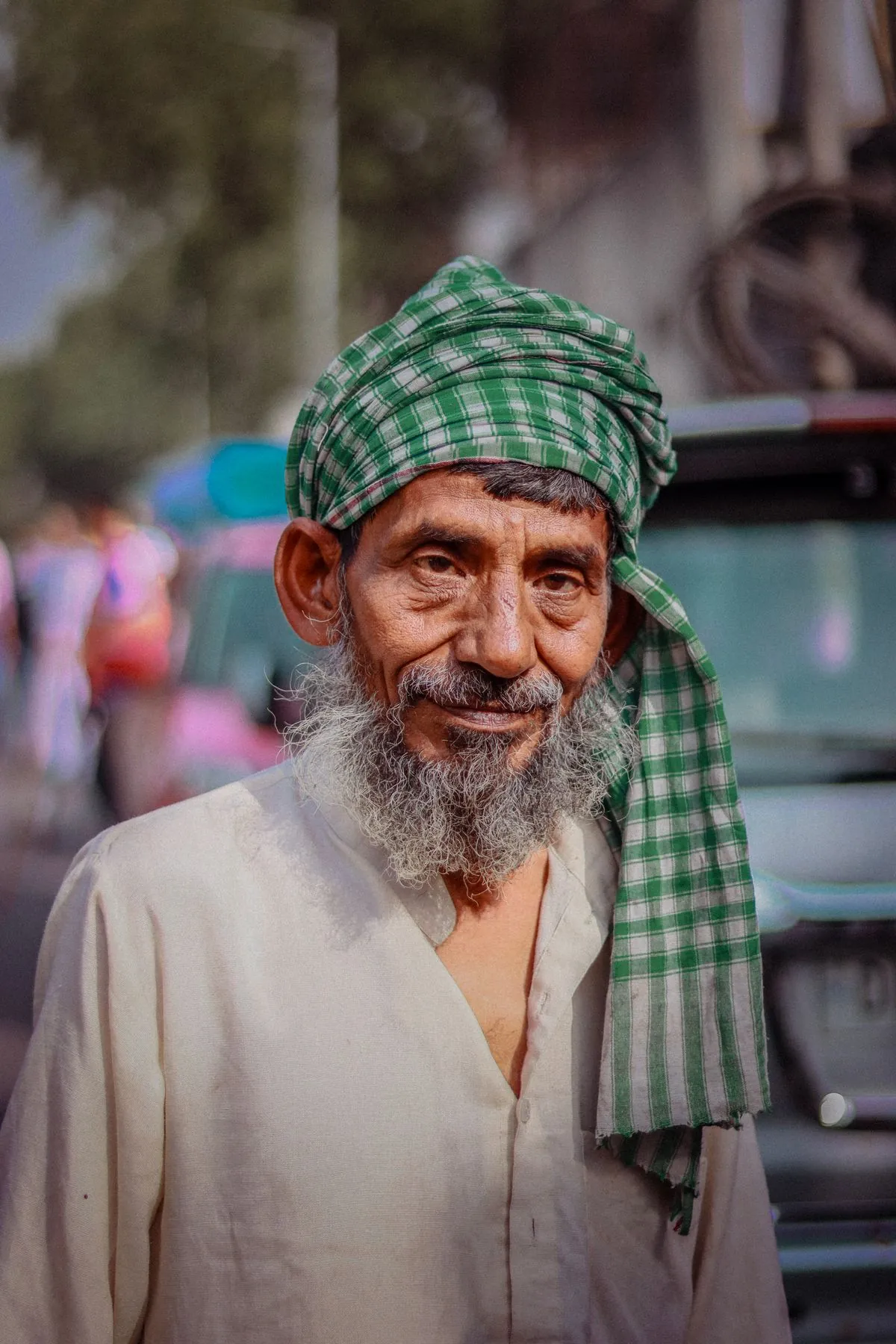 Portrait of an older man in a green turban on a street in New Delhi.
