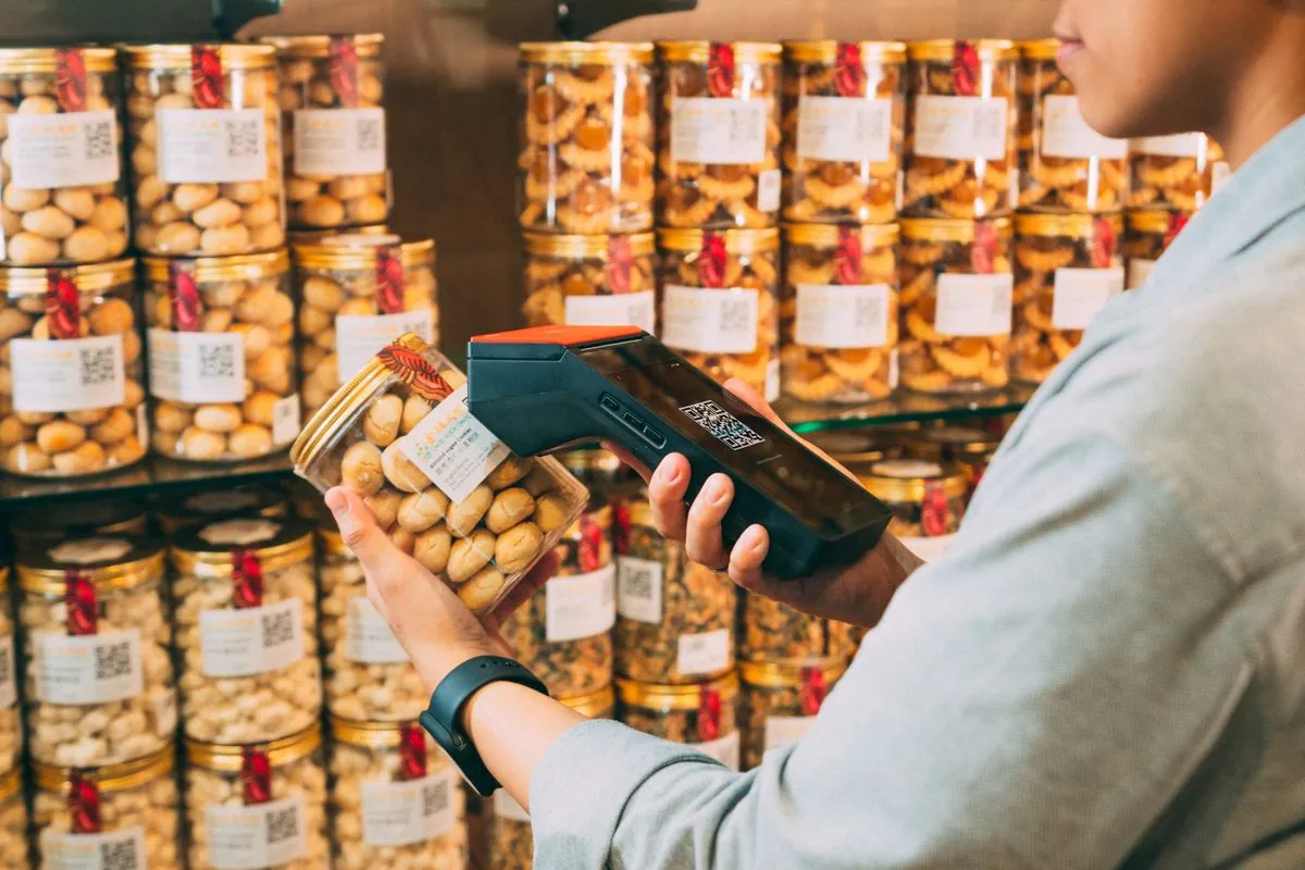A person scanning product codes on shelved jars with a handheld device.