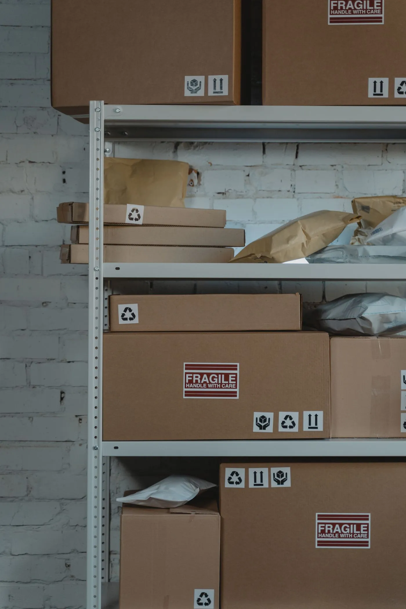 Cardboard cartons marked fragile stacked on warehouse shelving.